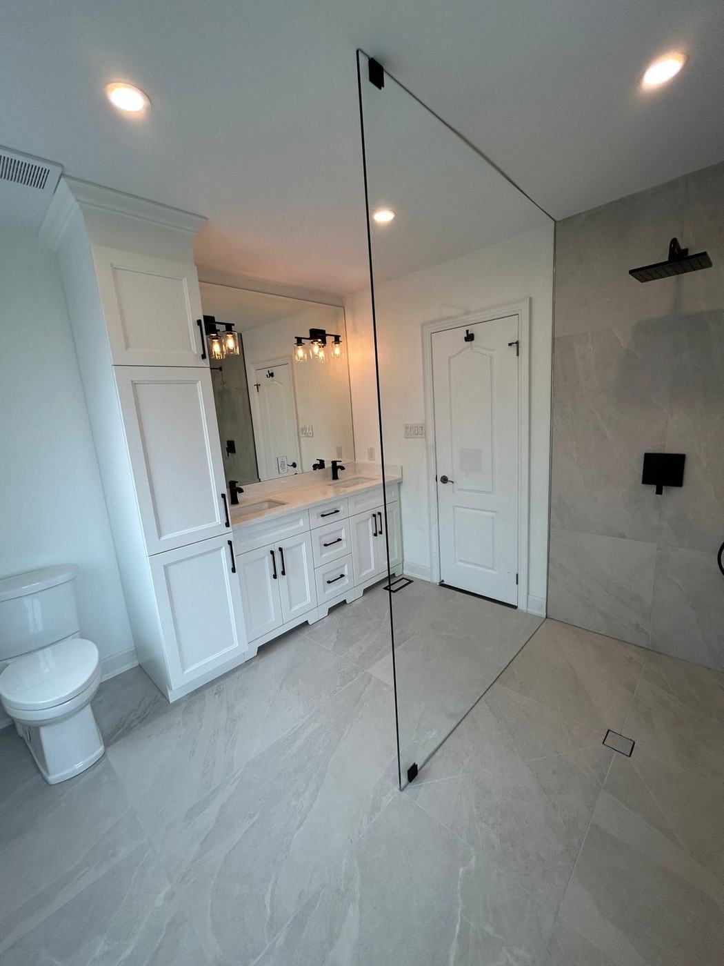 Curbless walk-in shower with a frameless glass panel and large stone-look tile in Maple, by NewGen Renovations Vaughan