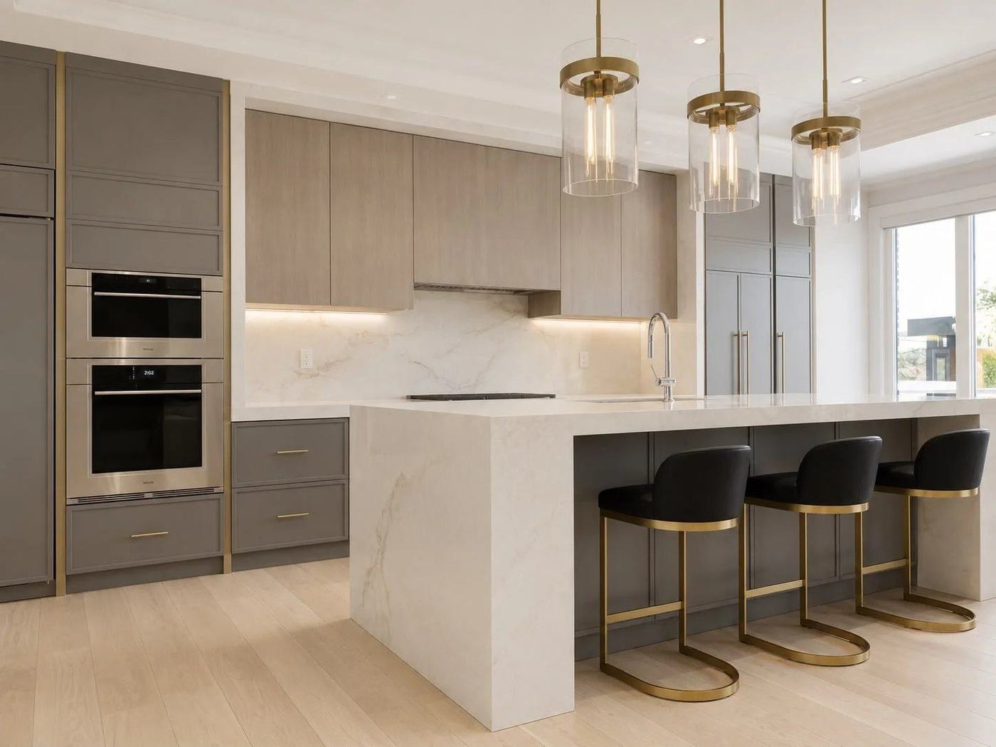 Grey and oak kitchen with a white waterfall island, glass pendant lights and gold-trim bar stools, by NewGen Renovations Vaughan