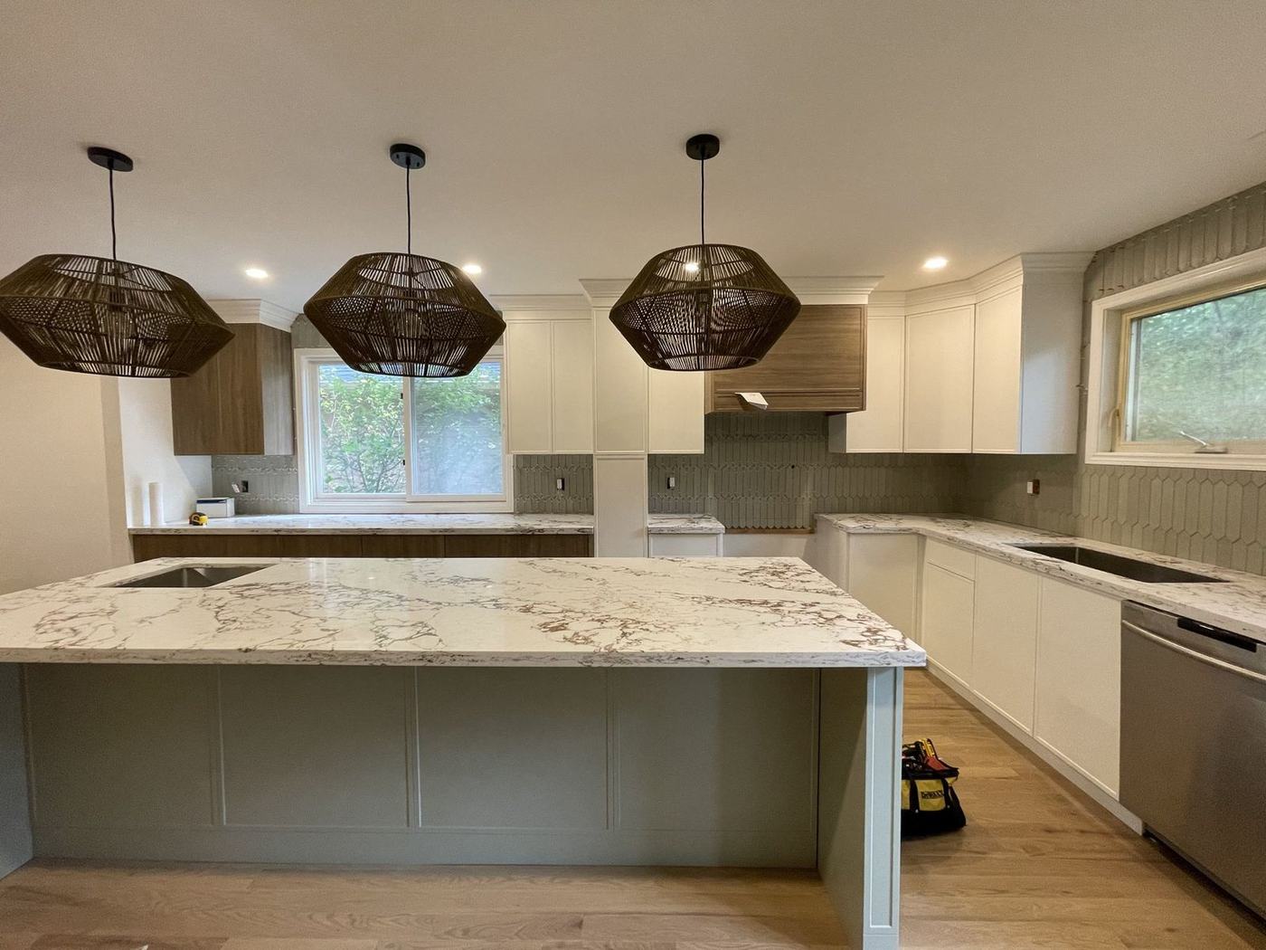 Kitchen renovation with a sage green island, marble-look countertop, three woven pendant lights and a green tile backsplash, by NewGen Renovations Vaughan