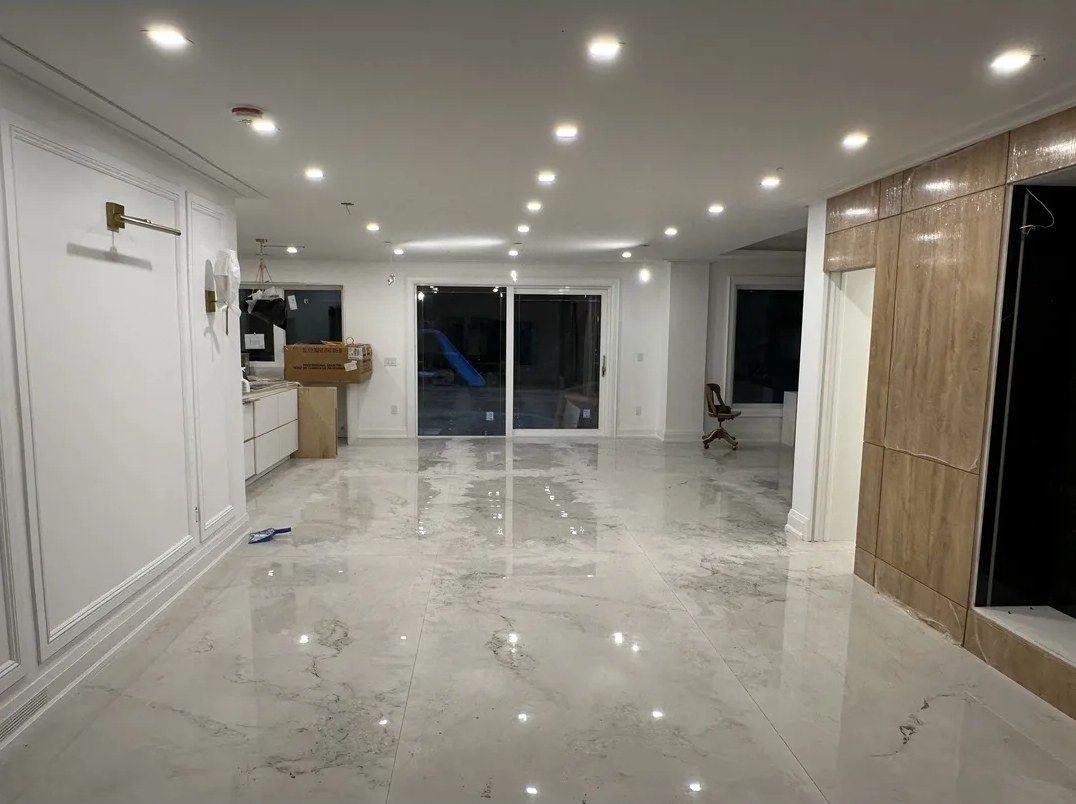 Polished large-format marble-look porcelain tile floor across an open-concept main floor with pot lights and wall panelling